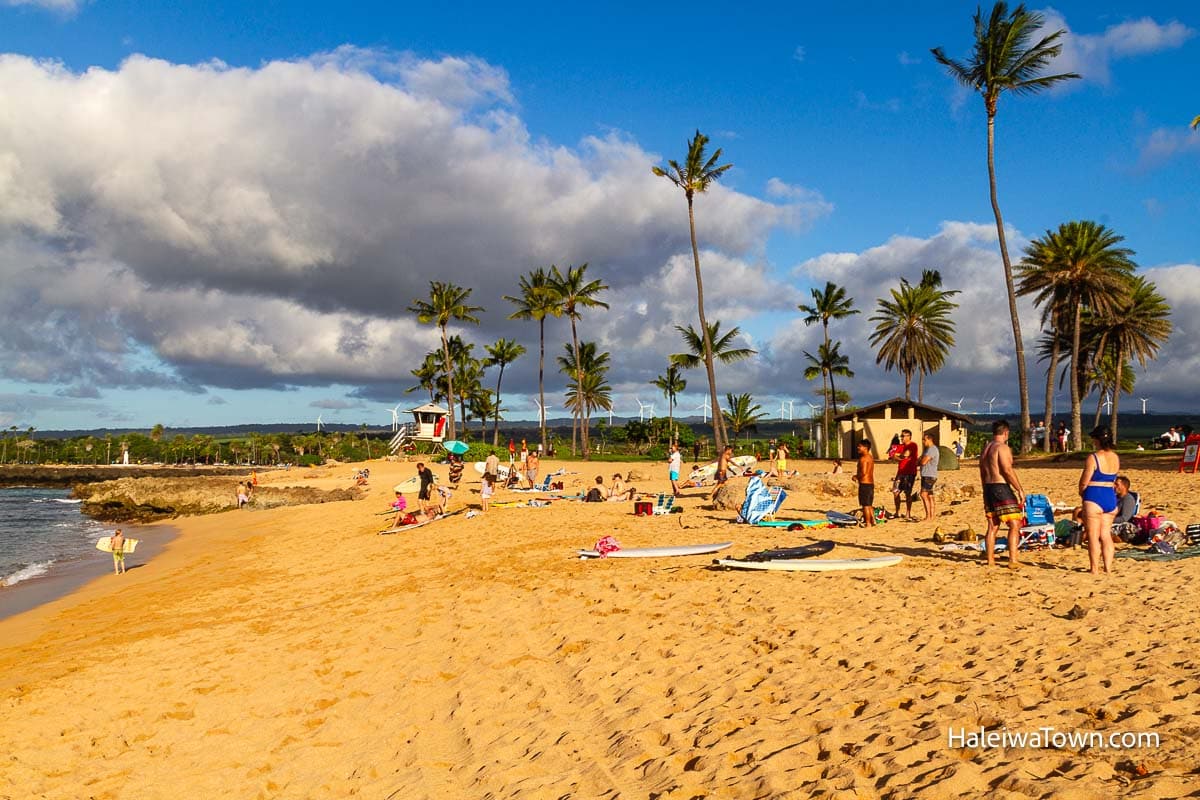 alii beach park full of people and surfers on the beach on a late afternoon sunny day