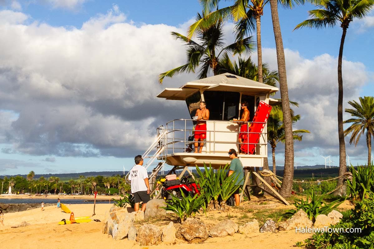 lifeguard tower on the beach at haleiwa with two male lifeguards speaking to two male tourists