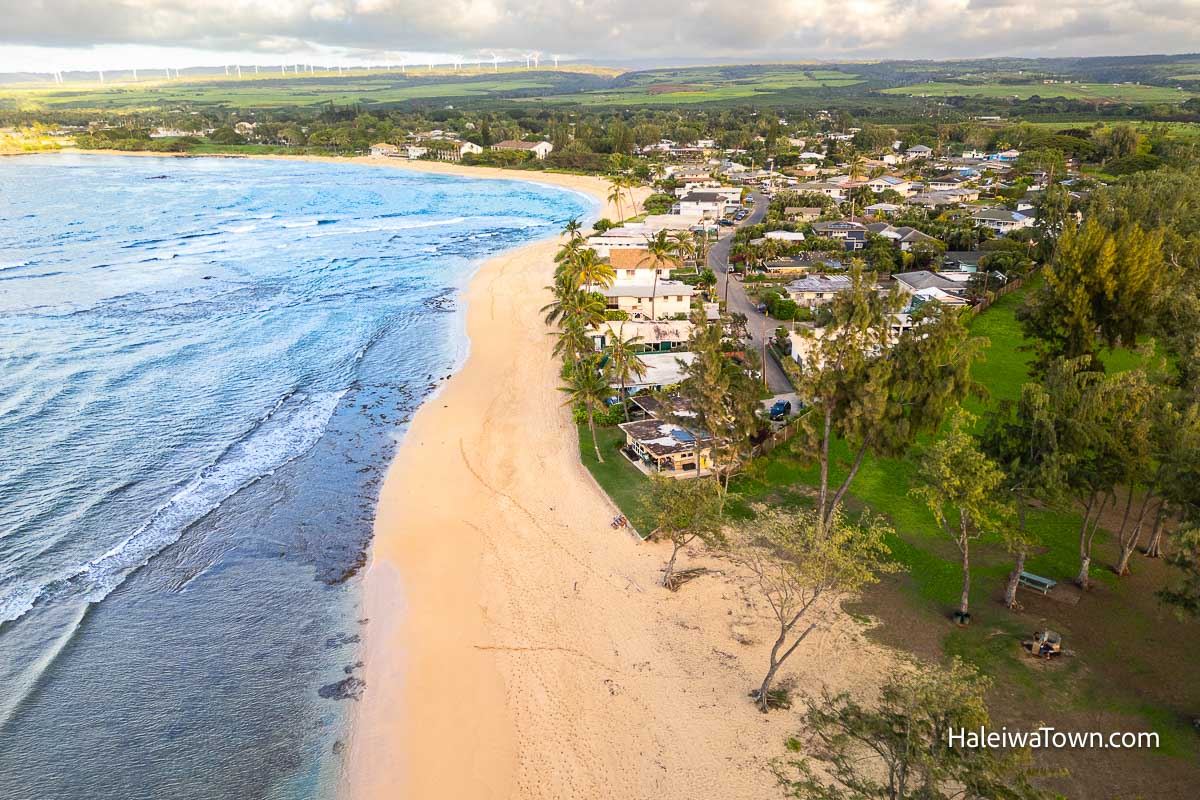 aerial view of vacation rental houses on the beach at haleiwa next to a green lush park