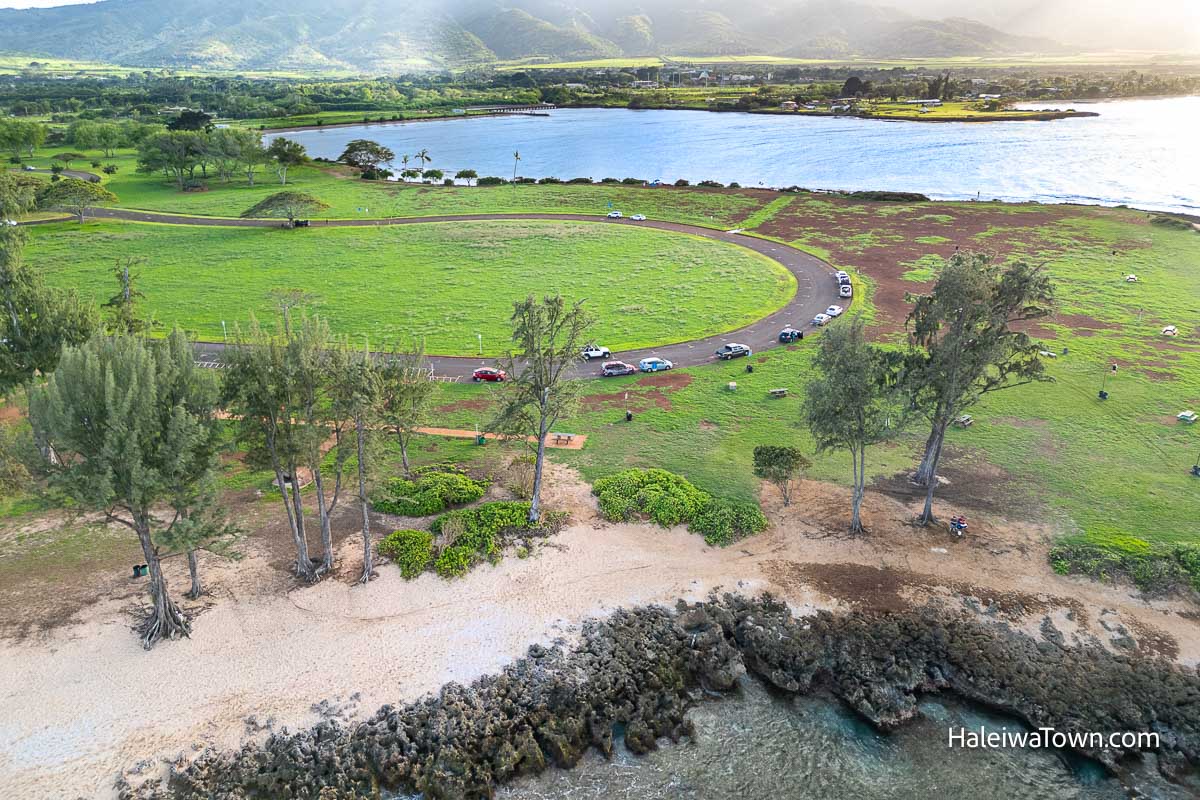 aerial view of kaiaka bay and it's green grassy park surrounded by the ocean and mountains