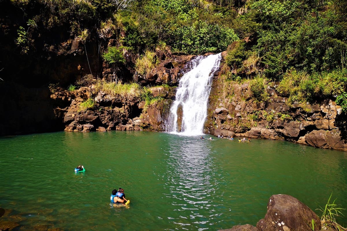 medium size waterfalls and a few people swimming around it