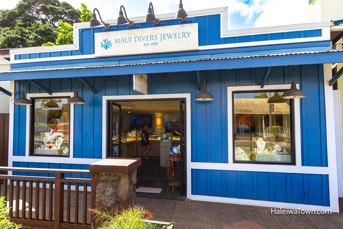 historic vintage retro blue building with large square windows and a front door for the store Maui Divers Jewelry and customers inside