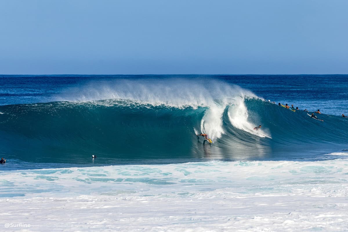 surfers dropping on a big wave at Backdoor and Pipeline