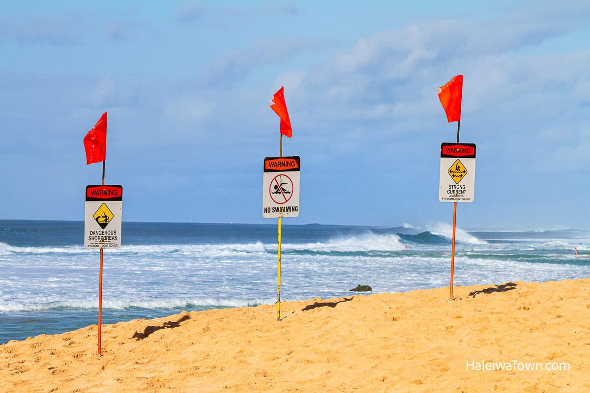 Warning signs at Ehukai Beach Park during dangerous surf conditions