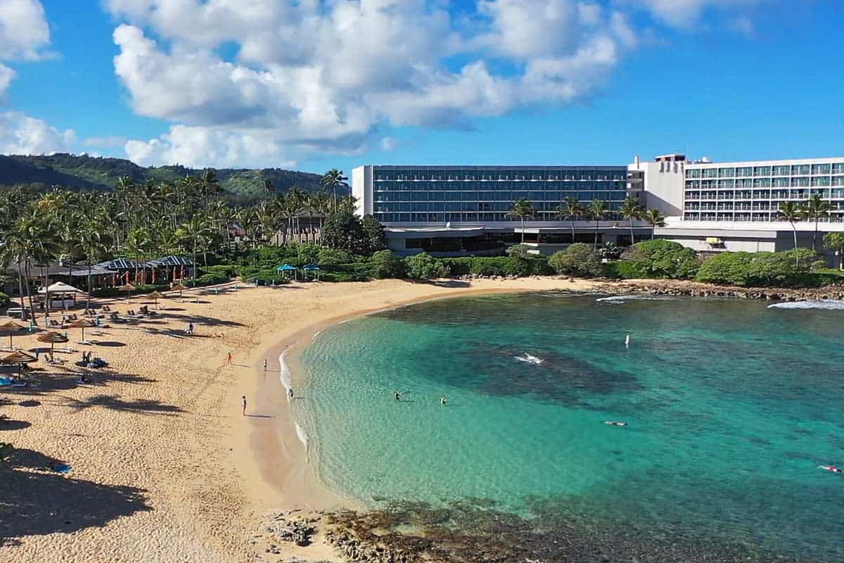 Aerial view of Kuilima Cove showing the calm water, sandy beach, and Turtle Bay Resort.