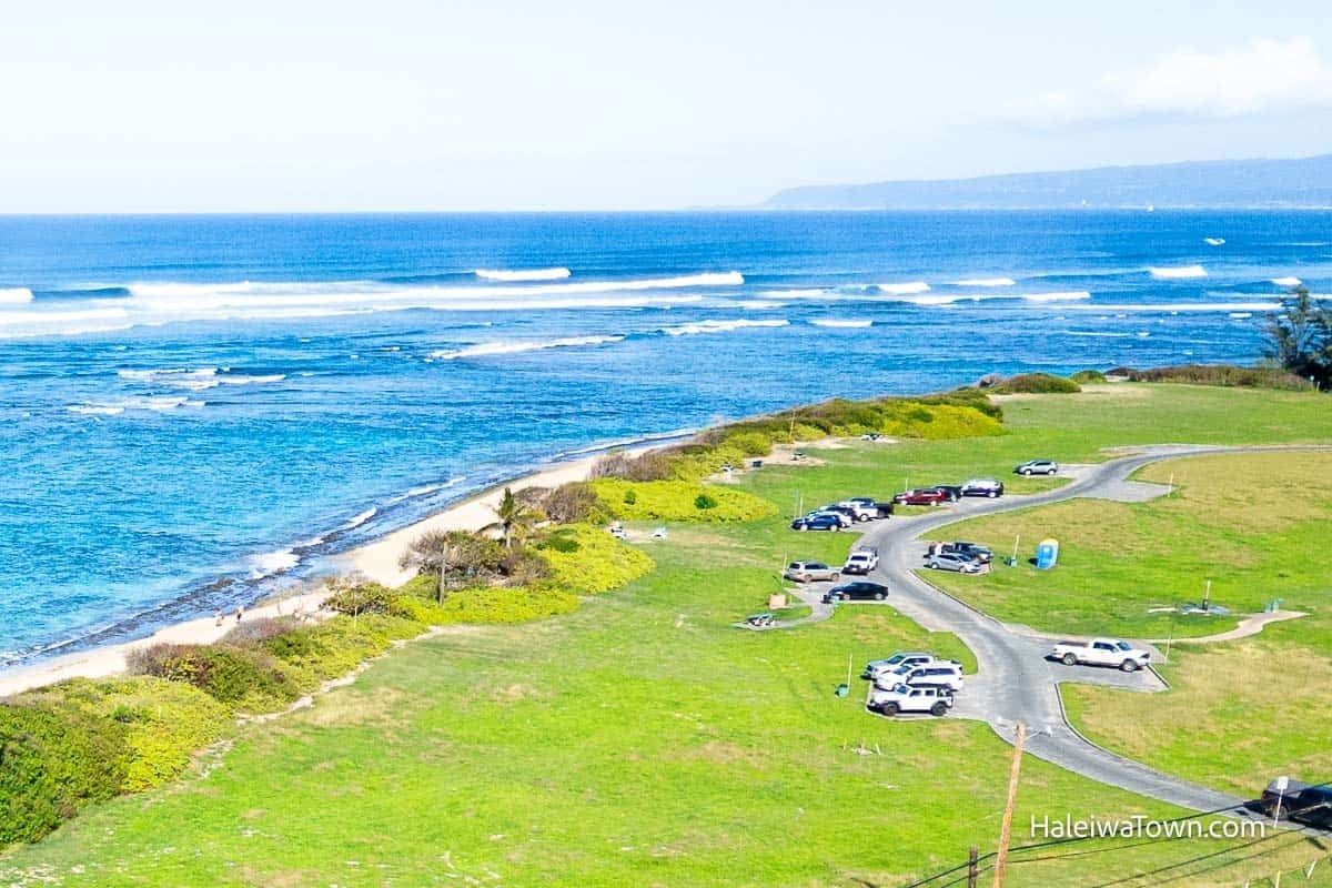 Aerial view of Mokuleia Beach Park showing the quiet shoreline, shallow reef, and waves breaking offshore.